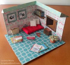 an open doll house with furniture and books on the floor in front of it that is made out of cardboard