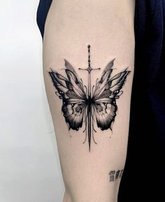 a black and white butterfly tattoo on the right thigh, with cross in the background