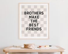 a poster with the words brothers make the best friends hanging above a table in a living room