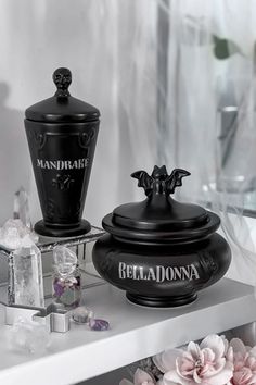 two black jars sitting on top of a white counter