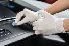 a person in white gloves is cleaning the hood of a car with a blue sponge