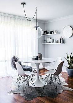 a dining room table with chairs and a rug on the floor in front of it