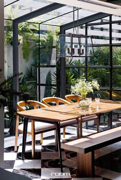 a wooden table sitting under a glass roof