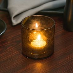 a lit candle sitting on top of a wooden table