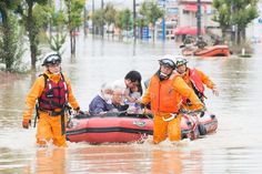 several people in life jackets and helmets are on a raft through flood waters with other people