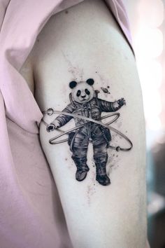 a panda bear tattoo on the left upper arm and shoulder with scissors in its hands