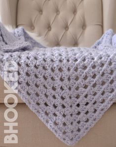 a crocheted blanket sitting on top of a couch next to a white chair