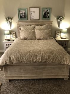 a bed with two lamps on either side of it and pictures above the headboard