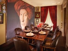 a dining room with a large painting on the wall and leather chairs in front of it