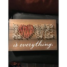 a wooden sign that says love is everything with string wrapped around the letters on it