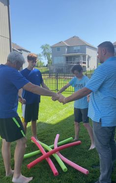 several people are holding hands in front of a group of plastic objects on the grass