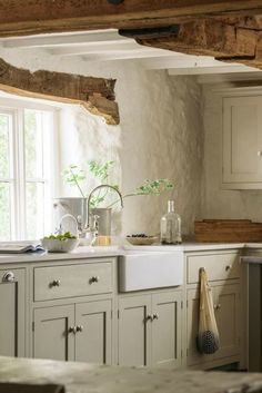 a kitchen filled with lots of white cupboards and counter top next to a window