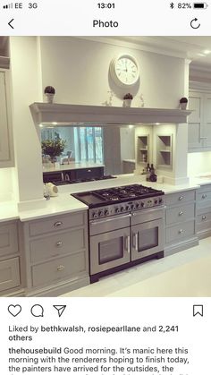 a kitchen with grey cabinets and a clock on the wall above the stove top oven