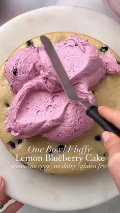 a person is cutting into a cake with pink frosting on it and there is a knife in the middle