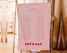 a pink sign that says let's eat hanging from a rack on the floor