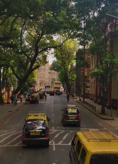 cars are driving down the street with trees lining both sides