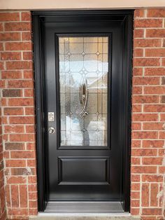 a black front door on a brick building with glass inserting the top half and bottom part