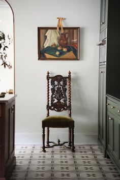 a chair sitting in the middle of a kitchen next to a painting on the wall