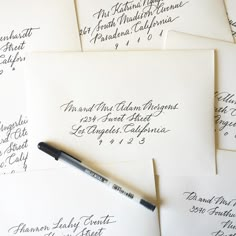 several envelopes with calligraphy on them and a pen resting on the top one