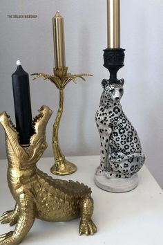 two gold and black candlesticks sitting next to each other on a white table