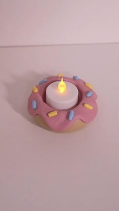 a pink donut candle holder sitting on top of a white table next to a wall