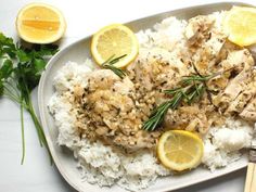 a white plate topped with rice covered in chicken and lemons