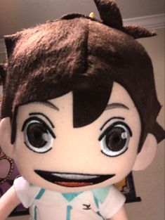 a close up of a stuffed animal wearing a white shirt and brown hair with big eyes