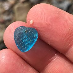 a blue heart shaped object sitting on top of a finger