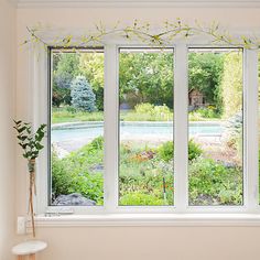 an empty room with three large windows overlooking a pool and garden outside the window sill