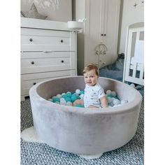 a baby sitting in a large round pool with balls on the bottom and inside it