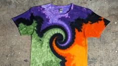 an orange, purple and green t - shirt with a spiral design