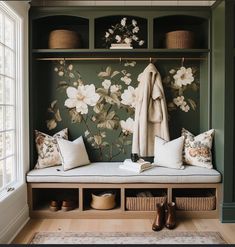 a bench with pillows and blankets on it in front of a floral wallpapered closet