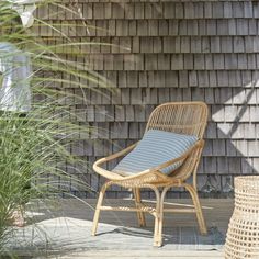 a wicker chair sitting on top of a wooden deck next to a tall grass plant