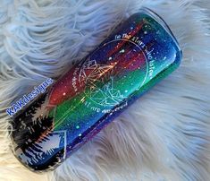 a rainbow colored tumbler sitting on top of a white fur covered floor with stars