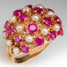 a gold ring with pink and white stones, pearls, and other jewels on it