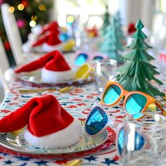 the table is set for christmas dinner with santa's hats and sunglasses on it