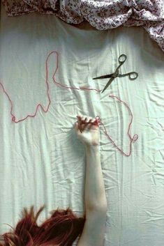 a woman laying on top of a bed next to a pair of scissors