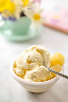 a bowl full of ice cream with a spoon in it and flowers in the background