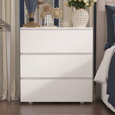 a white dresser sitting next to a bed in a bedroom