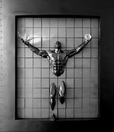 a sculpture of a man with his arms and legs spread out in front of a tiled wall