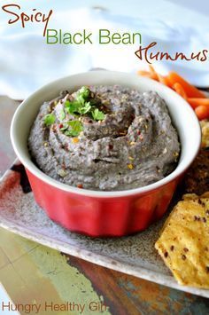 a bowl of black bean hummus with carrots and crackers