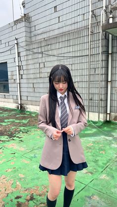 a woman in short shorts and a tie is standing on the ground with her hands together