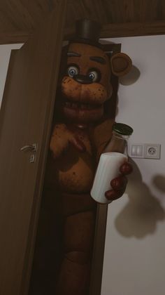 a stuffed animal holding a bottle in it's hand next to a light switch