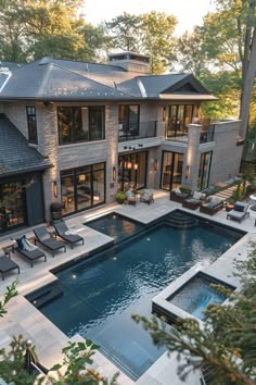 an outdoor swimming pool surrounded by lounge chairs and patio furniture in front of a large house