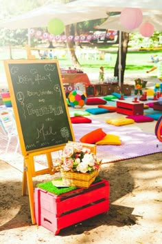 a chalkboard sign sitting on top of a red box under a white tent next to flowers