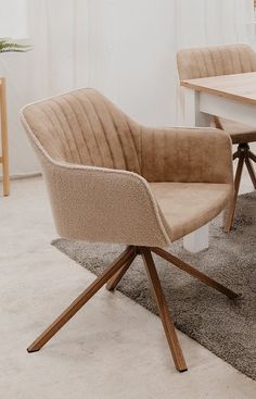 a chair sitting on top of a rug next to a wooden table and white walls