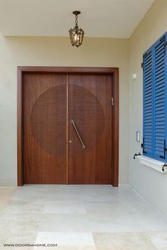 a large wooden door sitting in the middle of a hallway next to a window with blue shutters