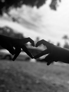 black and white photograph of two hands making a heart shape with their fingers in the air