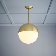 a white bed sitting under a gold colored light hanging from the ceiling in a bedroom