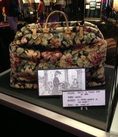 a handbag is on display in a glass case with a note attached to it